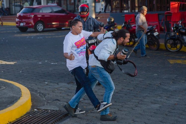 Agresión a periodista en abril pasado cuando iniciaron las protestas contra el gobierno. Foto LA PRENSA/EFE)